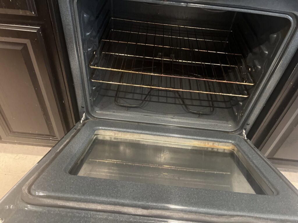 A dirty oven interior with a grimy glass door, indicating a need for professional cleaning by Jenny Can Cleaning Company in Canton, OH.