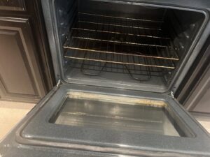 A dirty oven interior with a grimy glass door, indicating a need for professional cleaning by Jenny Can Cleaning Company in Canton, OH.