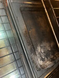The interior of a dirty oven with stained racks, ready for deep cleaning by A+ Residential Cleaning Services in Champaign, IL.