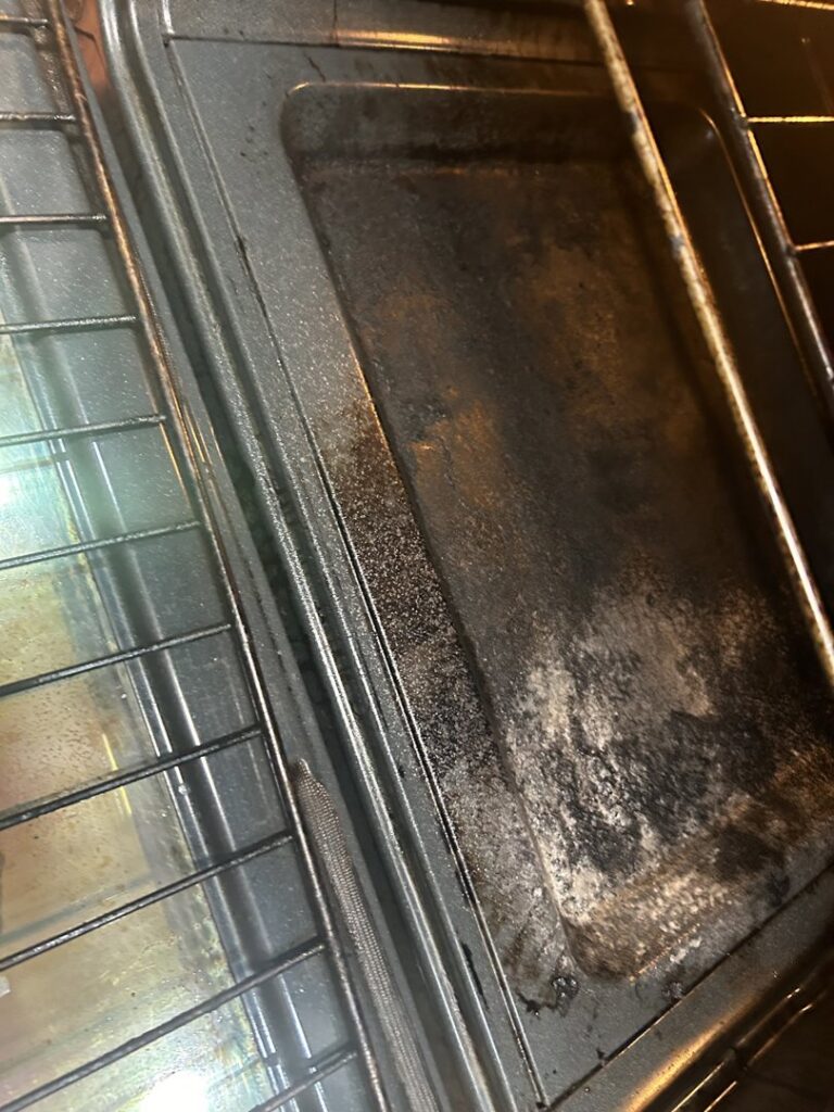 The interior of a dirty oven with stained racks, ready for deep cleaning by A+ Residential Cleaning Services in Champaign, IL.
