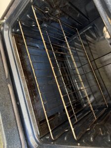 A dirty oven rack and interior, highlighting a 'before' cleaning situation that Messy To Clean in Aurora, IL can tackle.