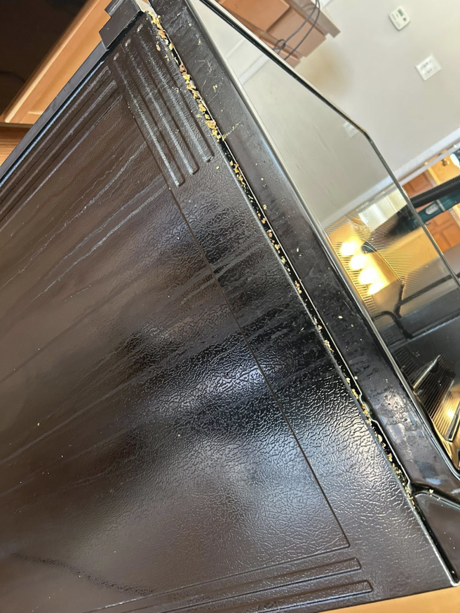 The dirty side of an oven with crumbs and debris, showing a common cleaning challenge for E & S Cleaning Services L.L.C in Nampa, ID.