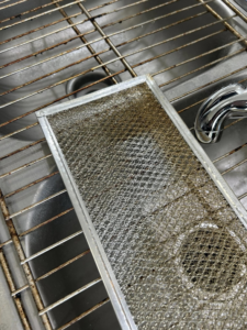 A dirty range hood filter in a sink, ready for deep cleaning by E & S Cleaning Services L.L.C in Nampa, ID.