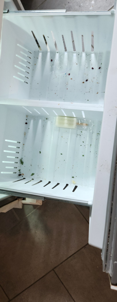 A dirty refrigerator drawer showing crumbs and debris before cleaning by Creativity Cleaning LLC in Detroit, MI.