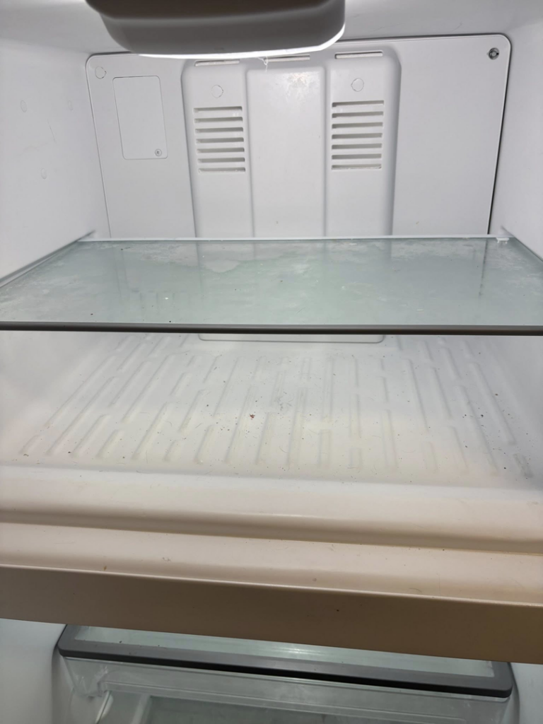 A dirty glass shelf inside a refrigerator, showing grime before cleaning by Sprinkled Clean in Bangor, ME.