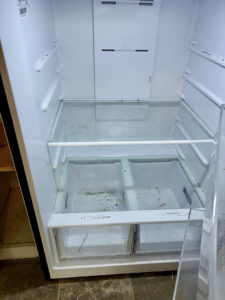 A dirty refrigerator interior with crumbs and debris on shelves, illustrating a 'before' cleaning scenario for Elite A&C Cleaning, LLC in Casper, WY.