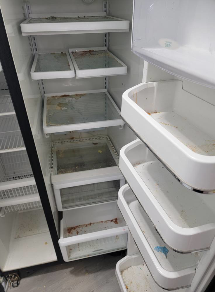 A dirty refrigerator interior with stained shelves and drawers before cleaning by Windham Cleaning in Akron, OH.