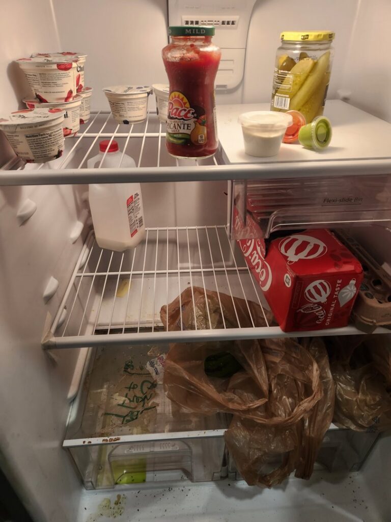 A dirty refrigerator interior with spills and crumbs, showing the 'before' state for deep cleaning by Rita's cleaning in Fort Worth, TX.