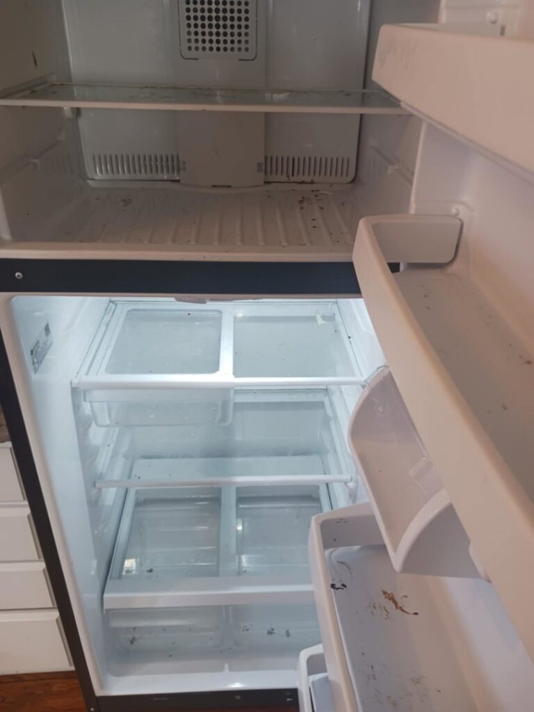 The interior of a dirty refrigerator with visible spills and crumbs, showing an area for deep cleaning by Cascade Fresh Cleaning Services in Grand Rapids, MI.