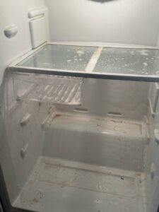 A dirty refrigerator interior being cleaned by New Clean Service in Wilmington, NC, highlighting their detailed cleaning service.