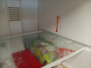 A close-up of a dirty refrigerator shelf with food spills, ready for cleaning by KB Cleaning in Bozeman, MT.