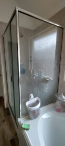 A dirty glass shower door and tub area with visible grime, indicating a 'before' state for Rita's cleaning in Fort Worth, TX.
