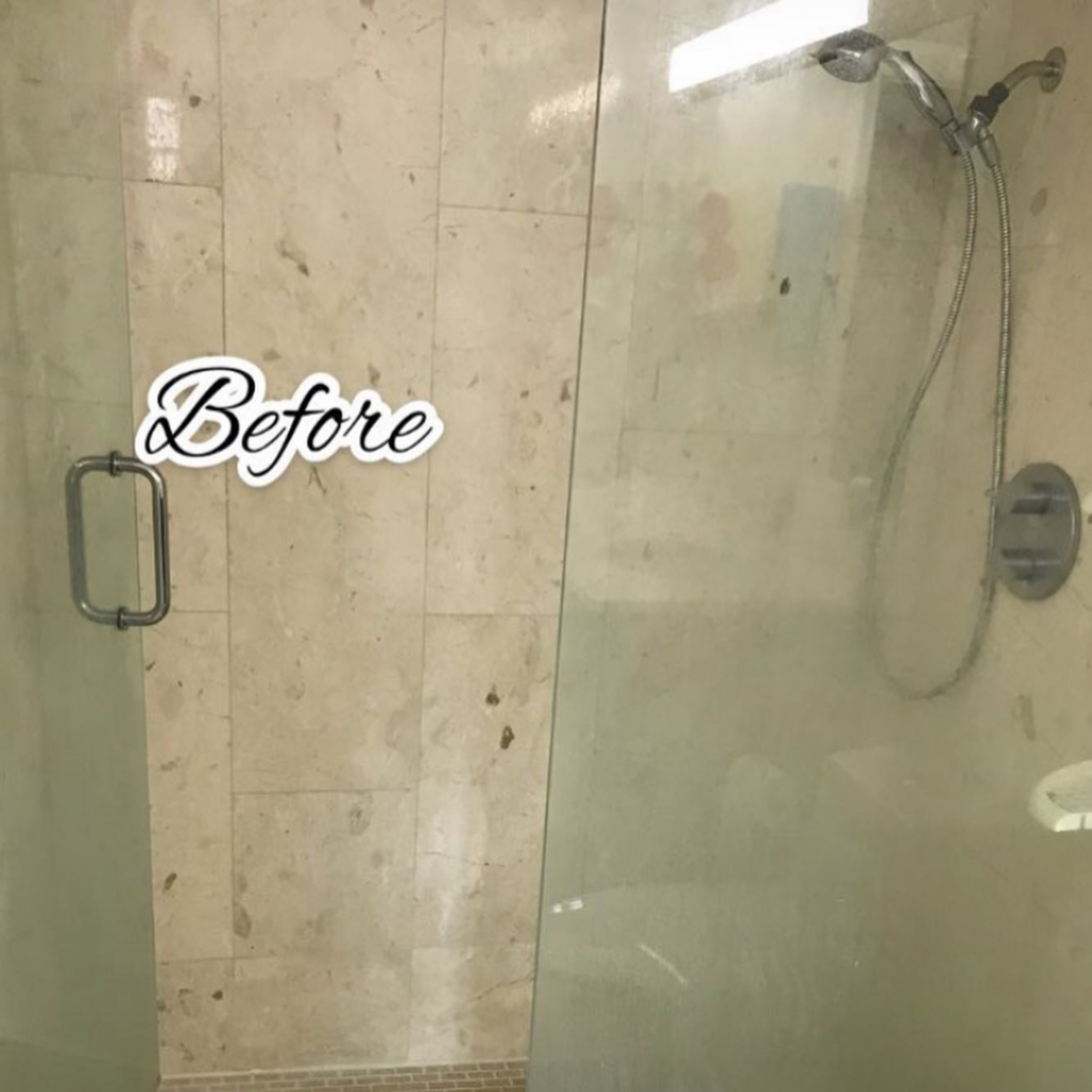 A dirty shower glass door and tiled wall with water spots before cleaning by Lourdes Home Cleaning in East Hampton, NY.