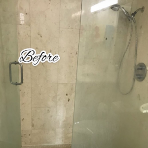 A dirty shower glass door and tiled wall with water spots before cleaning by Lourdes Home Cleaning in East Hampton, NY.