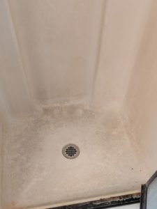 A very dirty shower floor with visible grime and water stains, representing a 'before' cleaning scenario for White Rose Cleaning in Idaho Falls, ID.