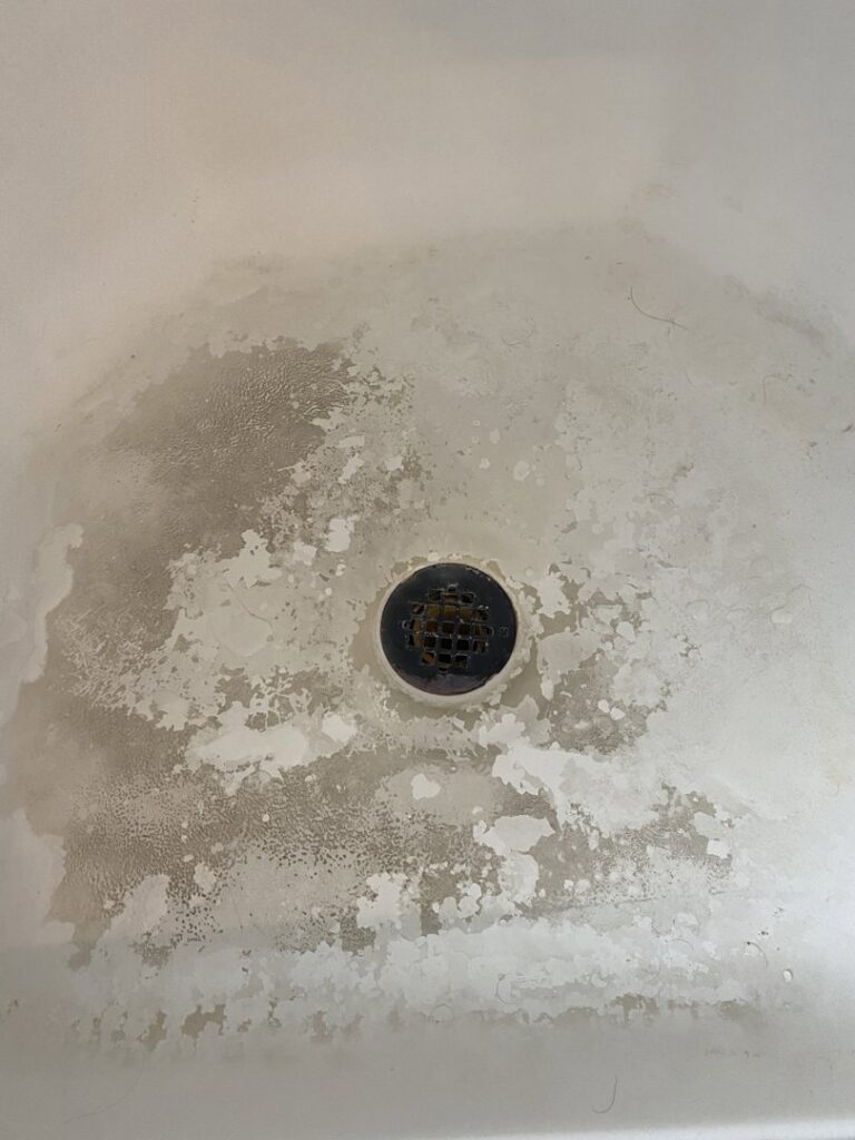 A dirty shower floor with significant hard water stains and grime, before cleaning by Jolley Services, INC in Bossier City, LA.