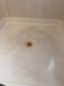 A dirty shower pan showing grime before cleaning by Lindi's Clean Living, LLC in Tucson, AZ.
