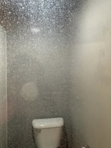 A shower wall covered in heavy water spots and grime, before cleaning by Spotless by Sam LLC in Green Bay, WI.