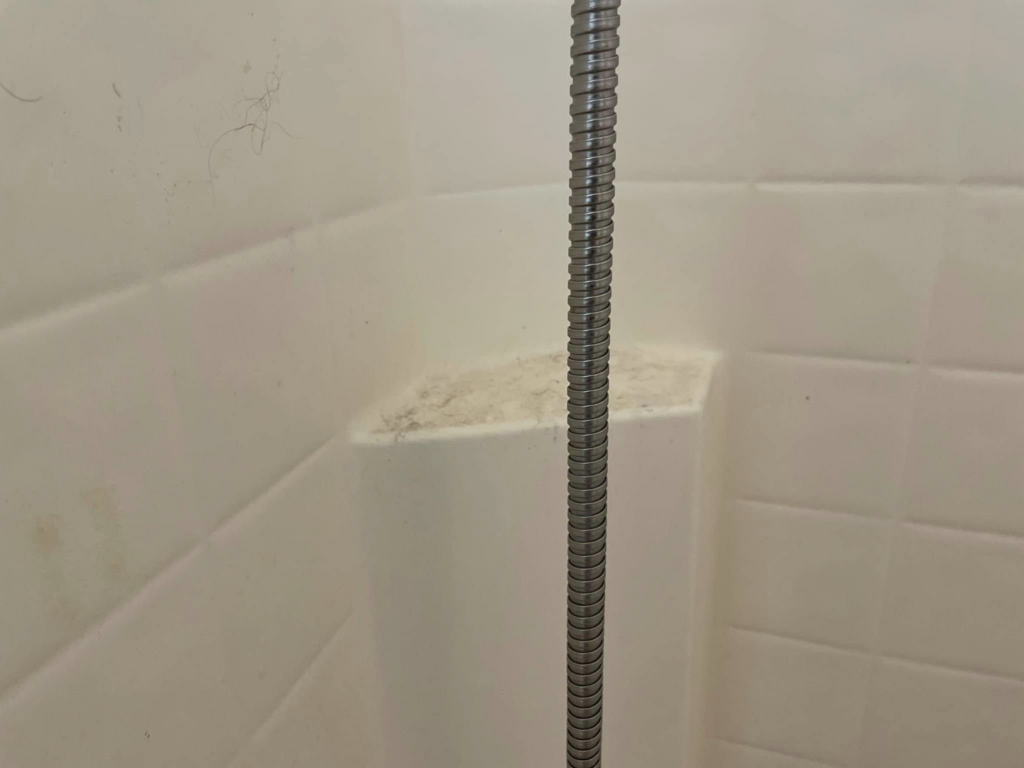 A close-up of a dirty shower wall with visible grime and residue, indicating a need for cleaning by Maid It Dirty Cleaning Company in Phoenix, AZ.