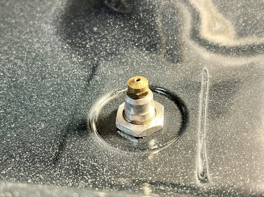 A close-up view of a dirty stove burner igniter, ready for cleaning by Masters Touch Cleaning Solutions LLC.