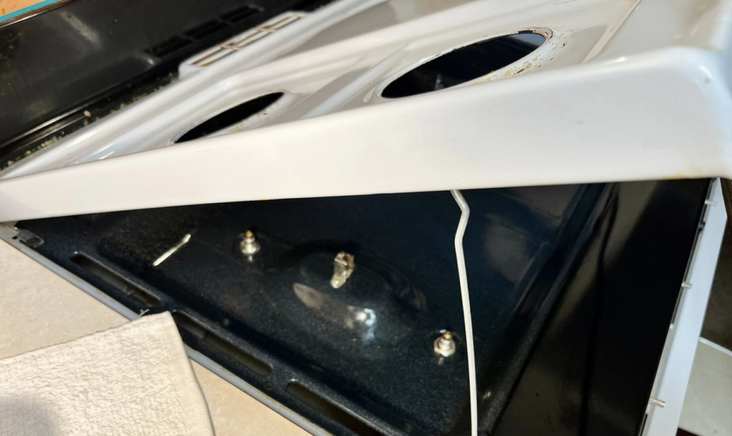 A dirty stove oven interior with the top lifted, showing grime before cleaning by Masters Touch Cleaning Solutions LLC.