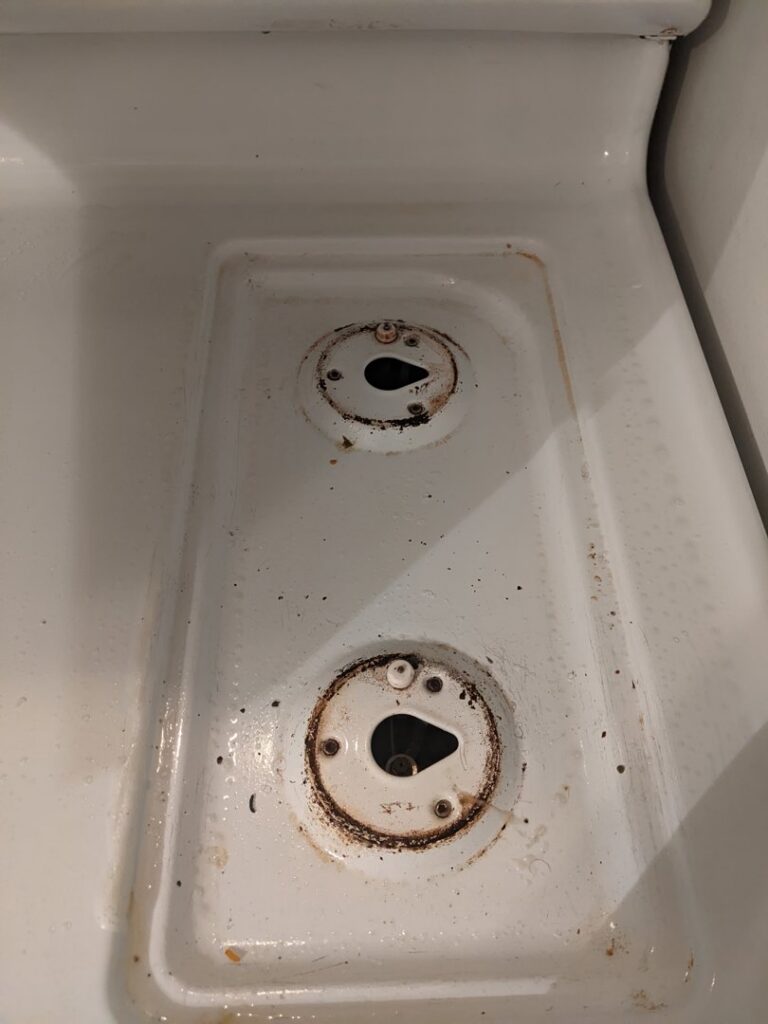 A dirty stovetop with removed grates, showing grime before a deep cleaning service by Chelle's Cleaning Services in Gary, IN.