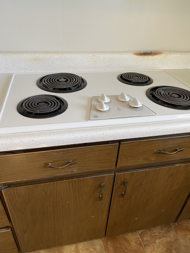 A dirty stovetop and stained countertop before professional house cleaning by J&RD Cleaning Service LLC in Bowie, MD.