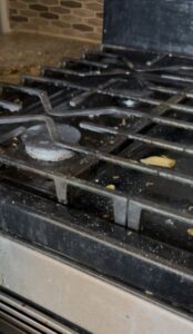 A dirty stovetop and range grates, indicating a need for deep cleaning by Bee-Dazzled Cleaning Service in Long Beach, CA.