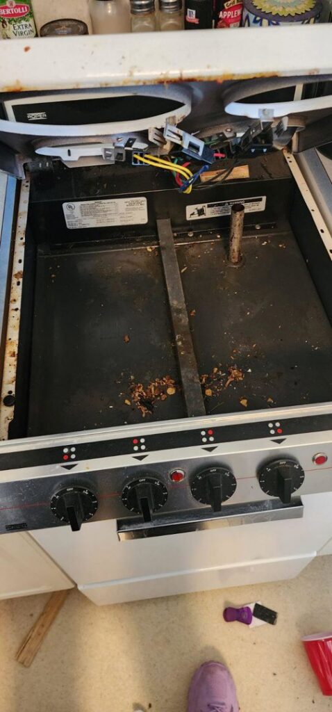 A very dirty stovetop with elements removed, revealing grease and food debris underneath, ready for deep cleaning by Sparkle & Shine of Iowa in Urbandale, IA.