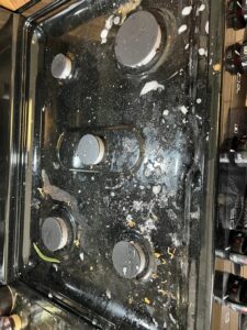 A dirty stovetop covered in food spills and grease before professional cleaning by Cinderellas Cleaning in Cerritos, CA