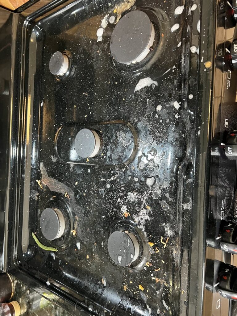 A dirty stovetop covered in food spills and grease before professional cleaning by Cinderellas Cleaning in Cerritos, CA