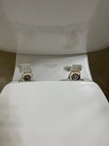 A close-up of a dirty toilet seat hinge, showing an area needing deep cleaning by JG Clean Solutions in Henderson, NV.