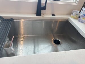 Close-up of dirty toilet seat hinges, showing grime before cleaning by J + M Cleaning, LLC in Flint, MI.