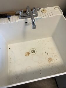 A dirty utility sink with visible stains and grime, indicating a need for thorough cleaning by Little Cubs Cleaning Services in Rochester, MN.