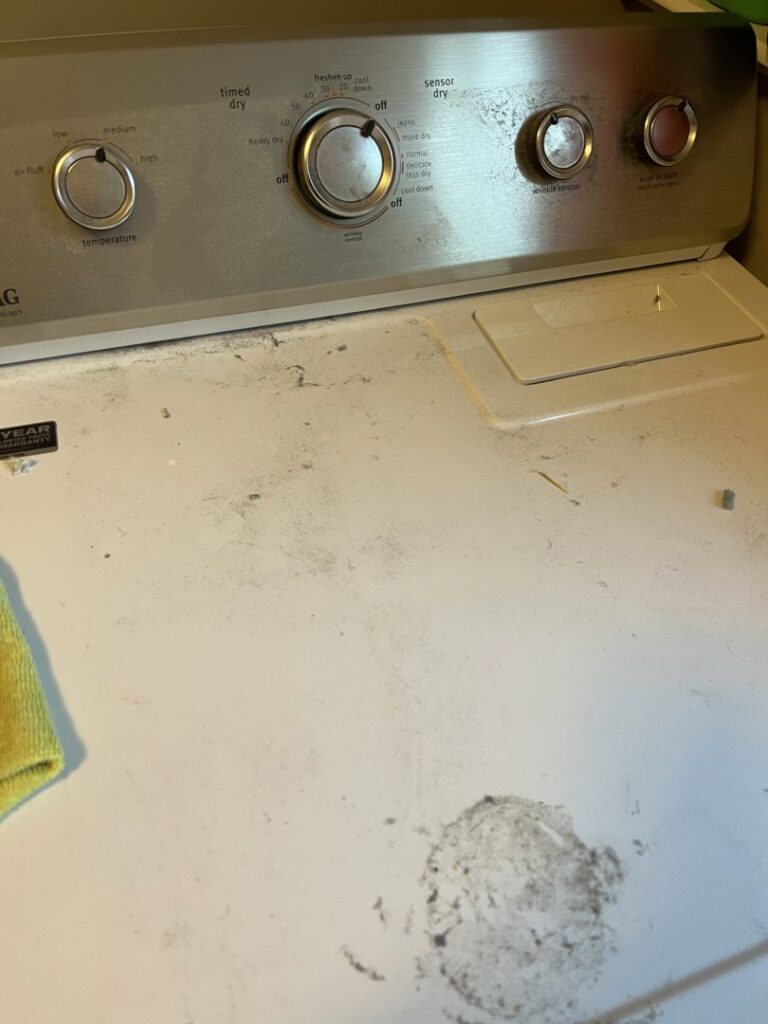 The dusty and grimy top of a washing machine, showcasing an area needing attention from Little Cubs Cleaning Services in Rochester, MN.
