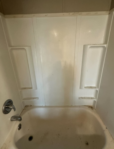 A dirty white bathtub and shower before professional cleaning by Dust Devil Cleaning in Eugene, OR.