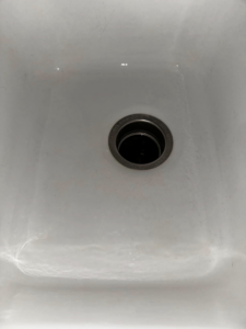 A dirty white kitchen sink showing grime before cleaning by Expert Cleaning On Demand in Tonganoxie, KS.