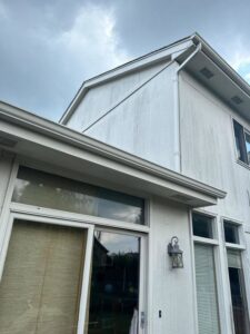A close-up view of dirty white siding and gutters on a house, indicating a need for exterior cleaning or replacement by Bishop Exteriors in Omaha, NE.