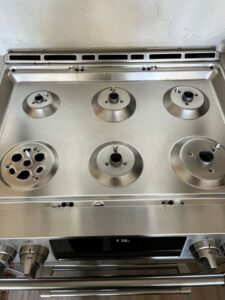 A dirty white stove top with food spills before professional cleaning by Sage & Soap Cleaning Co in Kansas City, MO.