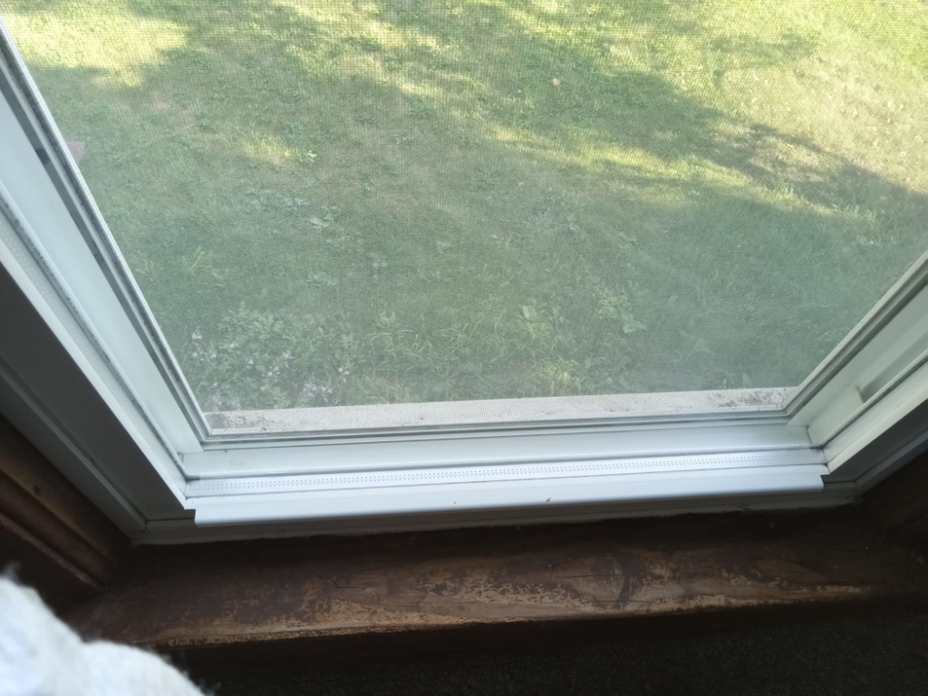A dirty window frame and screen, showing a 'before' state for house cleaning services by Sparkle & Shine of Iowa in Urbandale, IA.