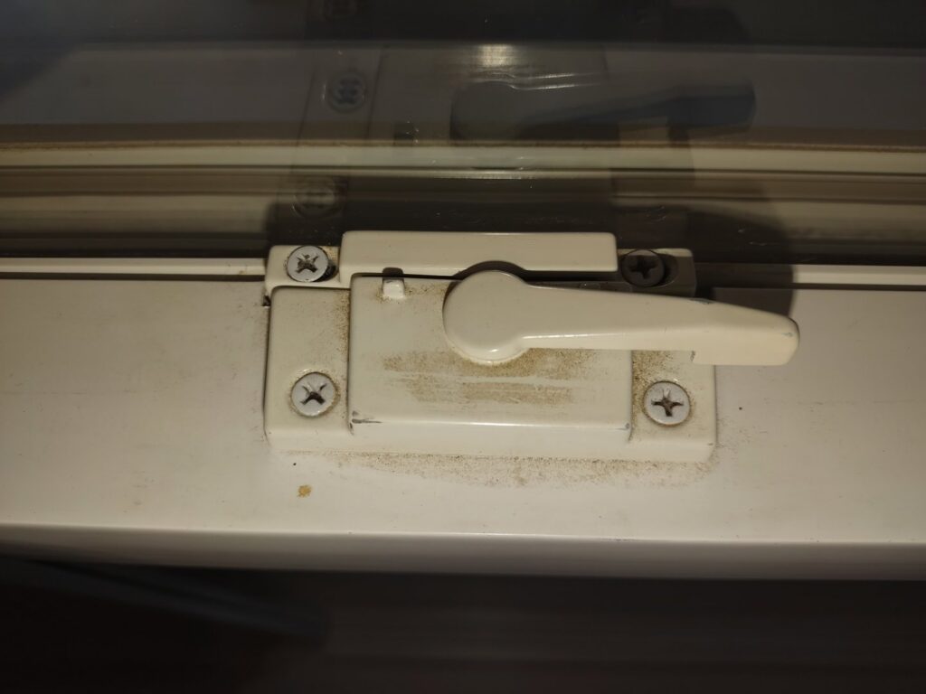 A dirty white window latch with visible dust and grime, before professional cleaning by Maid to Serve HIM in Cincinnati, OH.