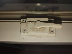 A dirty white window latch with visible dust and grime, before professional cleaning by Maid to Serve HIM in Cincinnati, OH.
