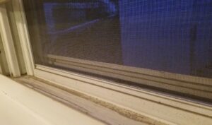 A close-up view of a dirty window sill, showing the need for professional cleaning from Home In Hand Cleaning Service in Concord, NH.