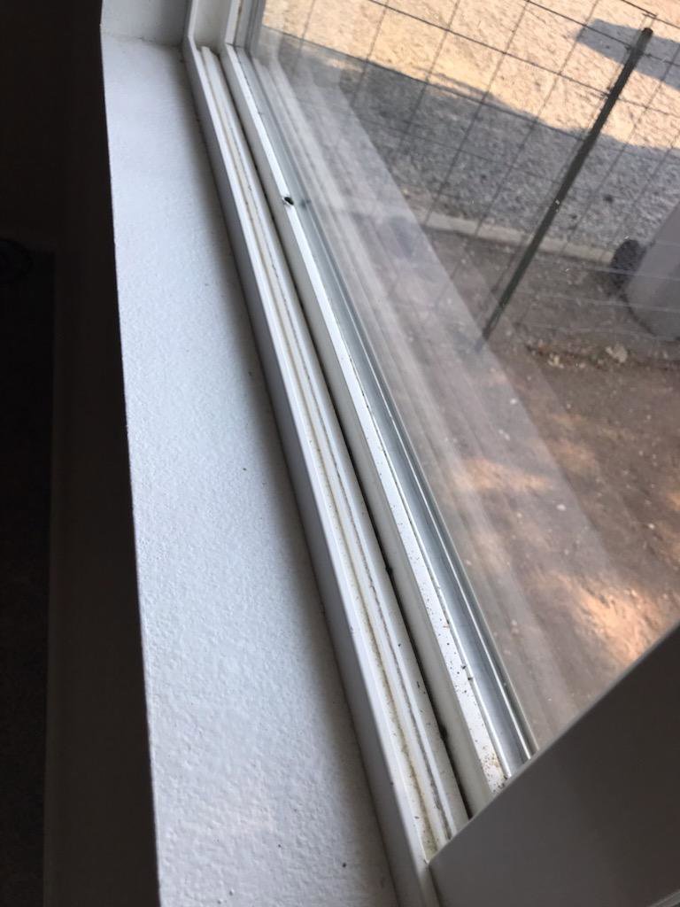 A close-up of a dirty window track and sill, indicating the need for professional cleaning by Blubyrd Cleaning Service in Boise, ID.
