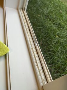A dirty window track with accumulated debris and a cleaning cloth, showing a detailed cleaning task by Little Cubs Cleaning Services in Rochester, MN.