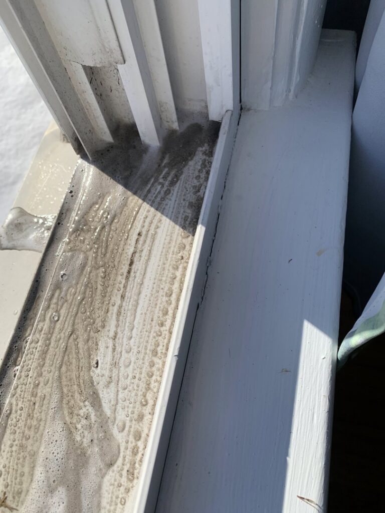 A dirty window track with soapy water, showing a house cleaning job in progress by Cuse Cleaning in Syracuse, NY.