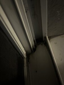 A close-up of a dirty window track filled with debris, showing an area ready for cleaning by A+ Residential Cleaning Services in Champaign, IL.