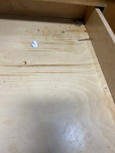 A close-up view of a dirty wooden drawer interior, highlighting an area for cleaning by A+ Residential Cleaning Services in Champaign, IL.