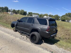 A disabled SUV missing a front wheel on the roadside, awaiting towing from Springfield Autobody and Towing in Springfield, IL.