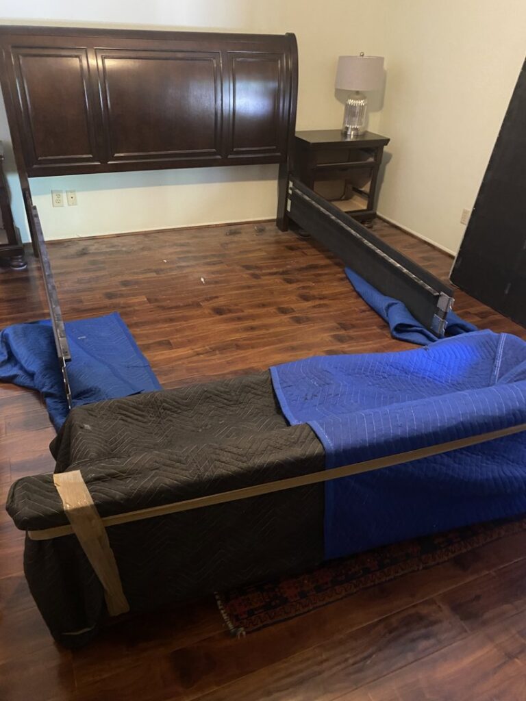 A disassembled bed frame and other items wrapped in protective blankets, prepared for moving by Moving Marvels in Tucson, AZ.